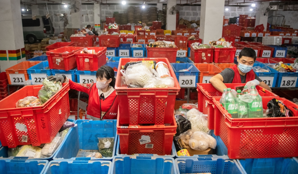 在多多买菜重庆江北五里店网格仓里，工人们根据团点订单进行分拣、装箱。受访者供图